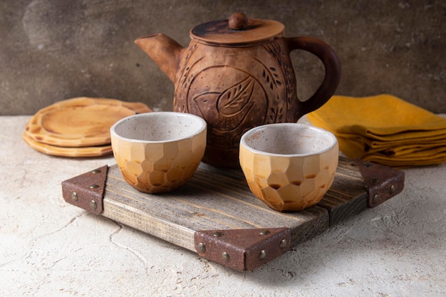 Ceramic vintage tea utensils teapot and tea mug Breakfast or dinner in rustic style serving with a wooden board