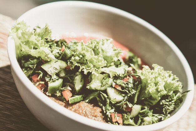 Ceramic white light bowl with mix green lettuce leaves spinach leaf salad ingredients fresh vegetables pureed red tomato serving plate Healthy vegan food cuisine Closeup View from above