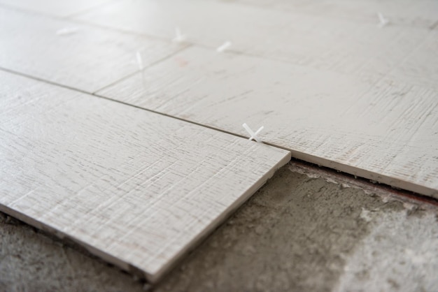 Фото Керамическая плитка с эффектом дерева и инструменты для укладки плитки на пол, незавершенная укладка напольной плитки. укладка напольной плитки.