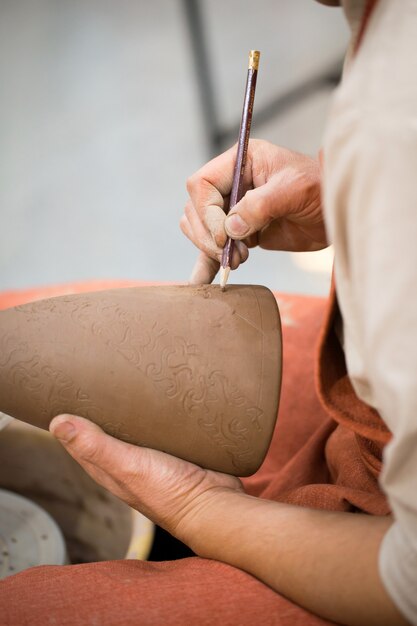 Ceramic workshop, the master puts otnament on unfired earthenware jug