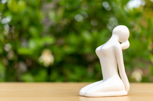 Ceramic Yoga Figurine of Woman doing yoga pose on wooden floor and green leaf background