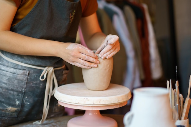 Фото Женщина-керамистка, формирующая кувшин для гончара в студии, посещает занятия по керамике после работы