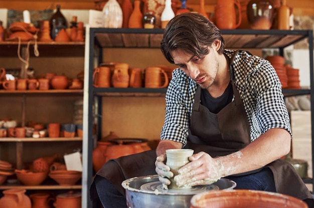 Ceramist uses potter's wheel and creates a handmade clay product.