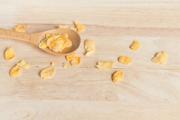 Cereal cornflakes spilling out from the wood spoon 