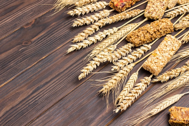 Barrette di cereali energia muesli e spighette di grano su una superficie di legno scuro. colazione equilibrata di proteine. vista dall'alto. copia spazio