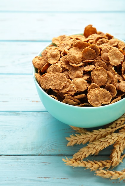 Foto fiocchi di grano di cereali, punte e chicchi di segale sulla tavola di legno blu. foto verticale