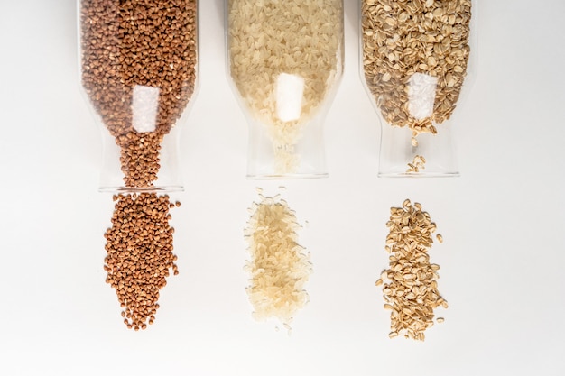 Cereals buckwheat rice oatmeal spilled out of glass containers on a white table