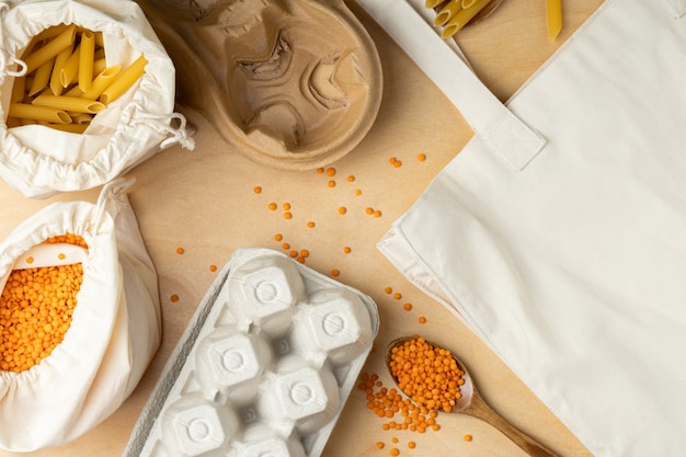 Cereals in eco cotton bags and wooden spoons on wooden table.Lentils,eggs and pasta in eco package.Zero waste shopping concept. no more plastic.