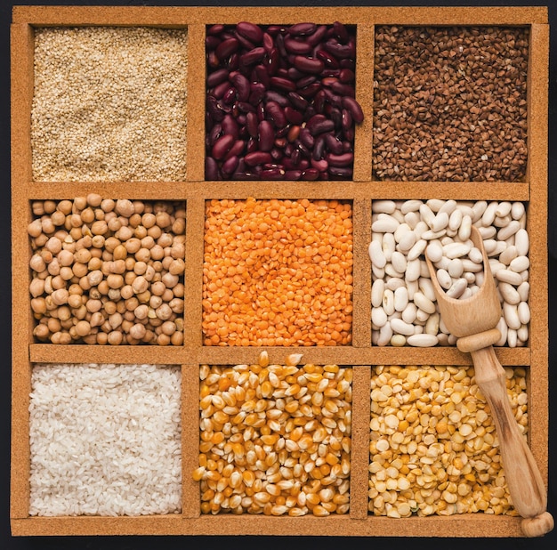 Cereals and legumes assortment in wooden box. Sesame, buckwheat, lentil, rice, peas, white and red beans, corn