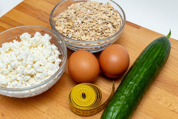 Cereals, measuring tape, farm cottage cheese eggs carrot close up on white background. healthy diet fat free eco sports nutrition 