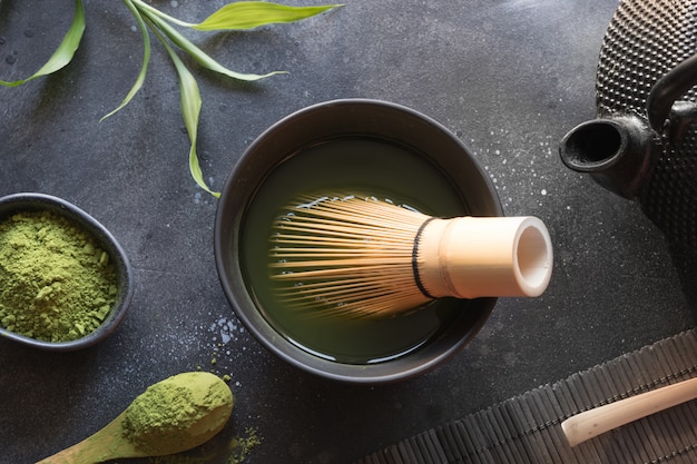 Photo ceremony green matcha tea and bamboo whisk on black table. top view. space for text.