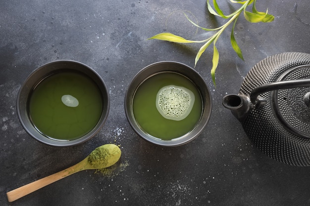 Ceremony green matcha tea and bamboo whisk on black table. Top view.