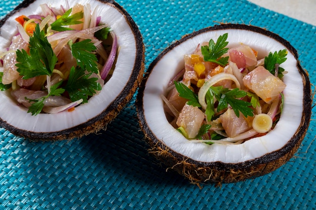 Photo ceviche dish - appetiser of fresh fish marinated in citrus with tropical fruits served in a coconut bowls.