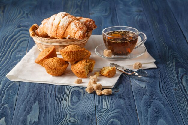 Photo ceylon black tea in glass cups, fresh croissants, vintage wooden background, selective focus