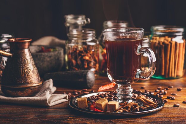 Cezve и чашка кофе на металлической тарелке с бобами рафинированным сахаром и восточными специями на деревянной доске