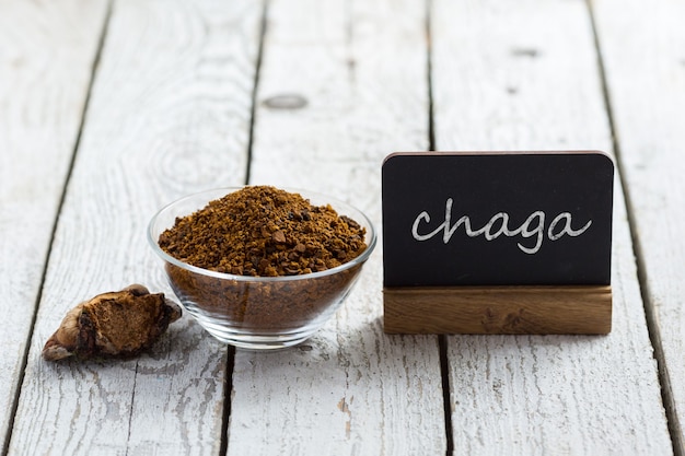 Foto fungo di betulla chaga, tavolo con iscrizione. bevanda ai funghi di betulla. fitoterapia. superfood biologico. tendenza funghi secchi e freschi