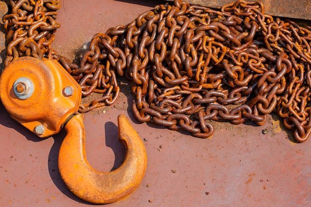 Chain hoist detail of a worn and rusty link in a large chain.