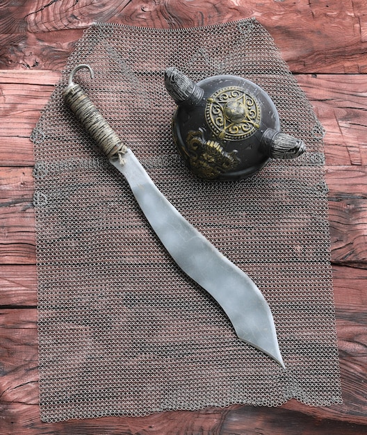 chain mail and sword on a wooden table