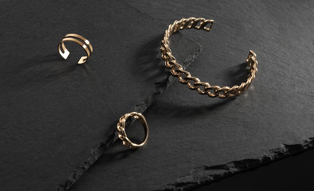 Chain shape golden bracelet and rings on black stone plates