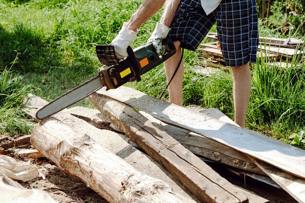 Фото Цепная пила в руках рабочего, разрезающего дрова