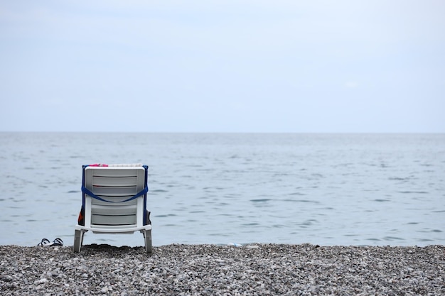 海とビーチのある小石の銀行の椅子