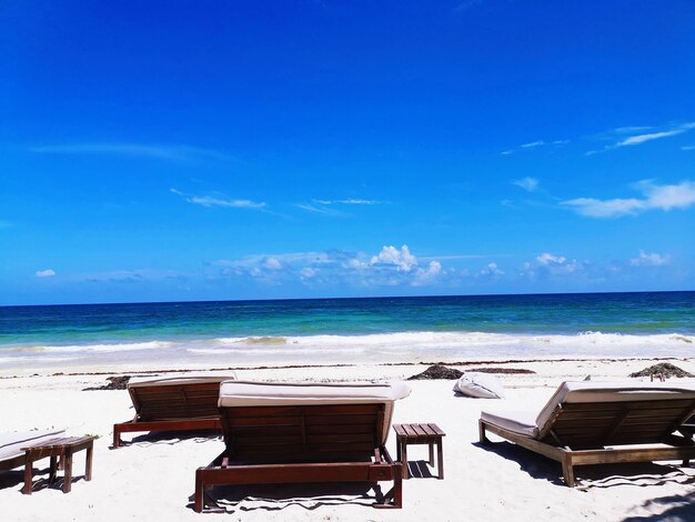 Chair on beach against blue sky