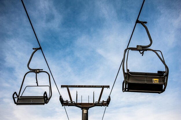 Photo a chair lift is up against a blue sky with a few clouds.