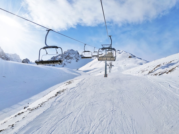 The chair lift in sunny day. An incredible mountain landscape around them.