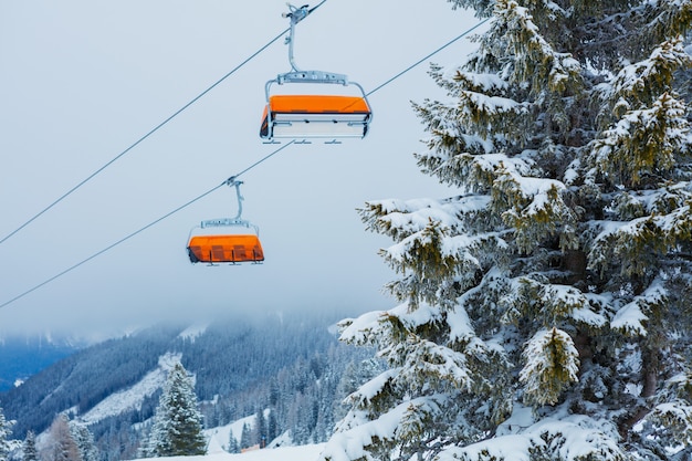 Кресельный подъемник с лыжниками на горнолыжном курорте Альпы