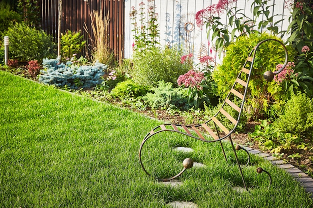 A chair near the house. Blooming flowers and a lawn. copy space.