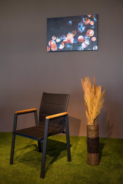 A chair and a plant are on the floor in front of a wall that has a painting of a moon and stars.