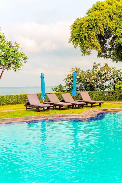 chair pool and umbrella around swimming pool with ocean sea background