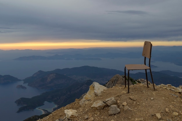 Foto sedia in cima a una montagna con tramonto sul mare con versando raggi di sole splendente tra le nuvole