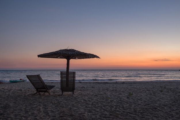 Sedia, ombrellone, tramonto sulla spiaggia al tramonto.