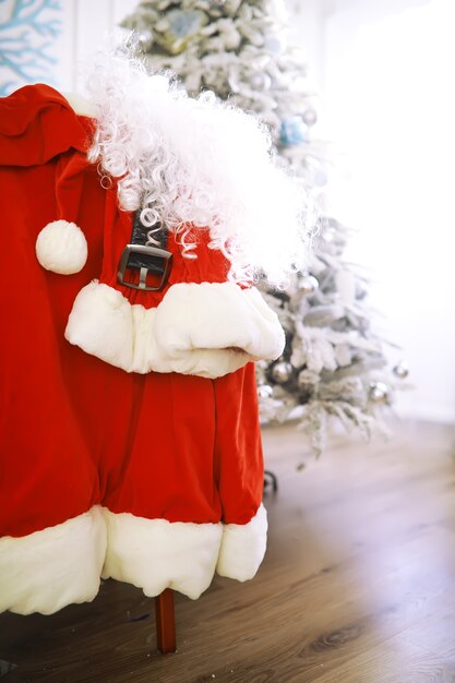 Chair with clothes from Santa Claus. Santa costume hanging in white room