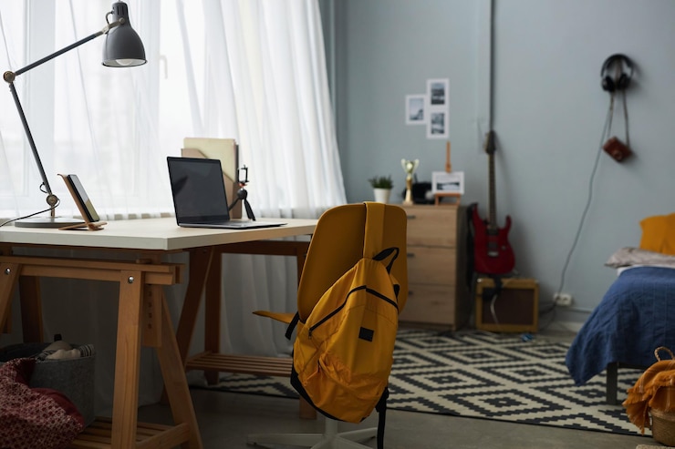 Photo chair with yellow backpack standing in front of desk with lamp and laptop
