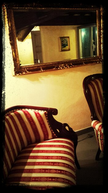 Photo chairs against mirror on wall at home