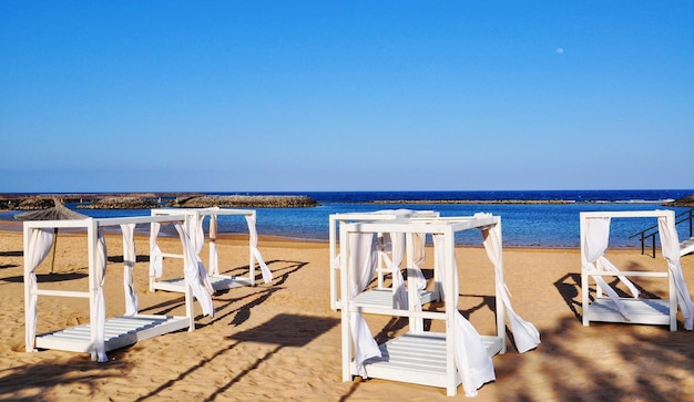 Chairs on beach against clear blue sky