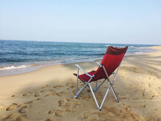 Chairs on beach against clear sky