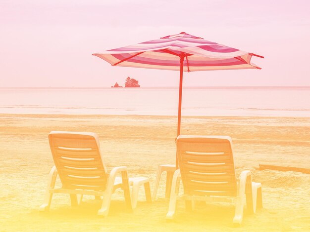 Chairs on beach against sky during sunset