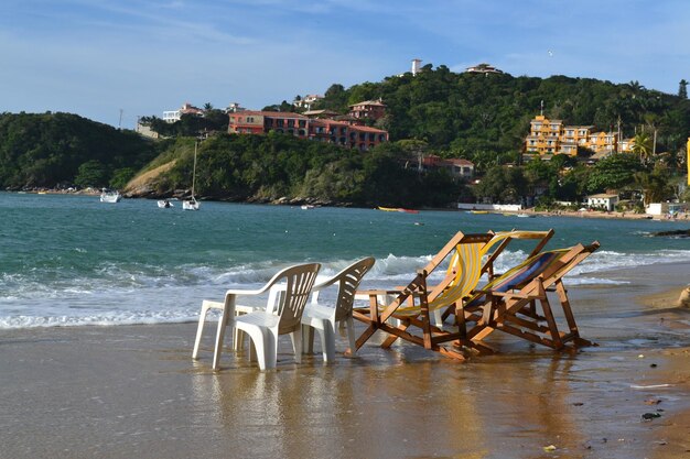 Chairs on beach by sea against sky