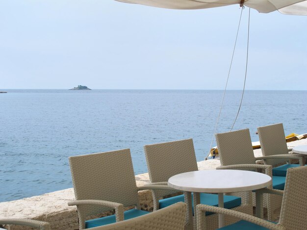 Chairs and table by sea against sky