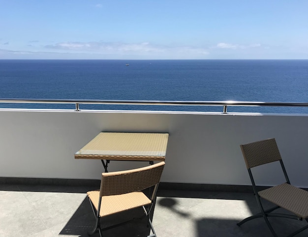 Chairs and table by swimming pool against sky