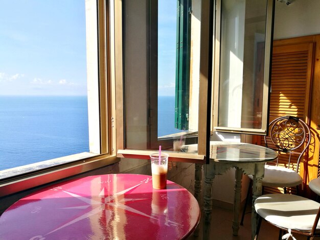 Chairs and table by swimming pool against window