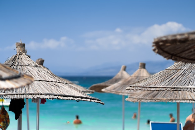 Chairs And Umbrella In Palm Beach Tropical Holiday Banner. Beach palm trees and sky. Summer vacation travel holiday background concept. Tropical scenery. Mountains. Post card.