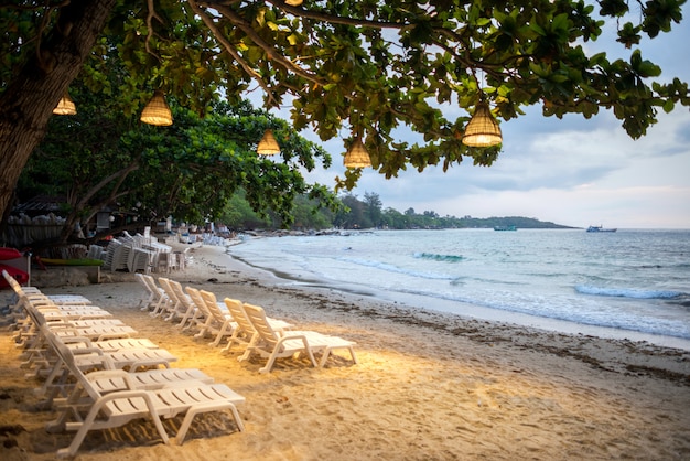 Chairs with Lamp on a tree is foreground on the beach in Samet island in the morning, Koh Samet Thailand.