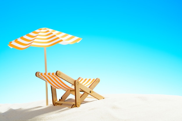 A chaise longue under an umbrella on the sandy beach, sky with copy space