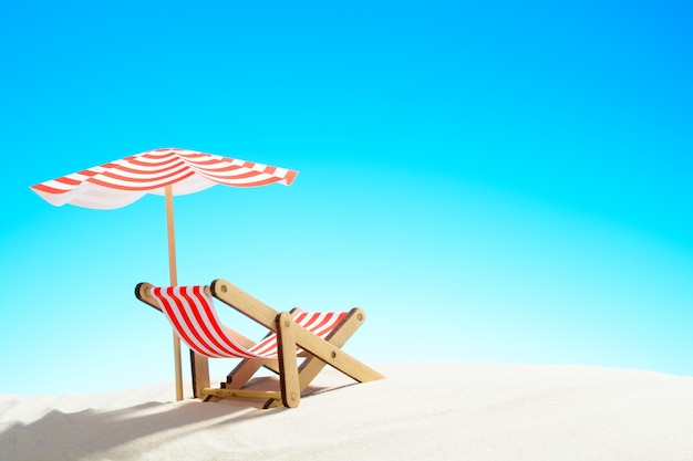 A chaise longue under an umbrella on the sandy beach, sky with copy space