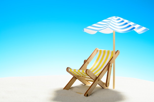 A chaise longue under an umbrella on the sandy beach with copy space