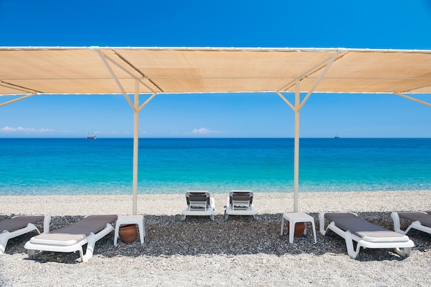 Chaise zitkamers onder de tent op het kiezelstrand in Kemer, Turkije.